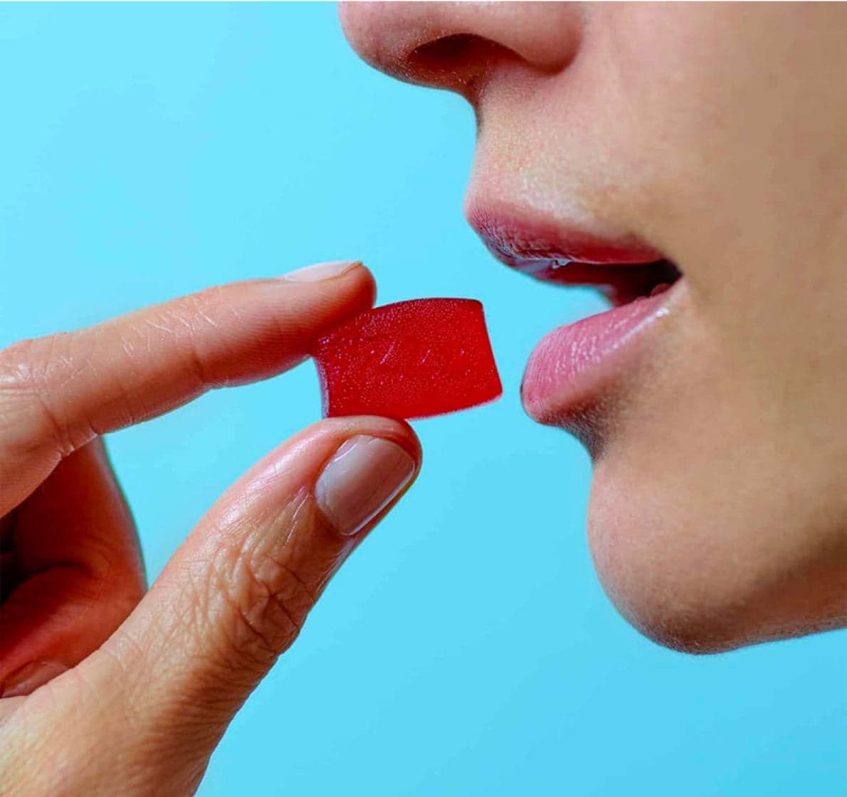 Close-up of a person about to eat a raspberry-red sleep gummy
